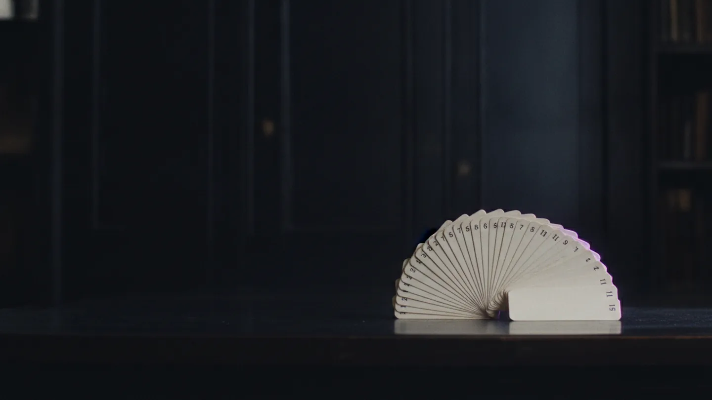 Numbered index cards fanned across a dark desk under violet edge lighting.